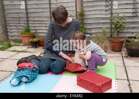 Little girl opening her birthday presents with her grandmother Stock Photo