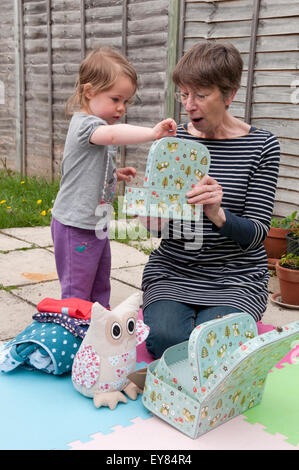 Little girl opening her birthday presents with her grandmother Stock Photo