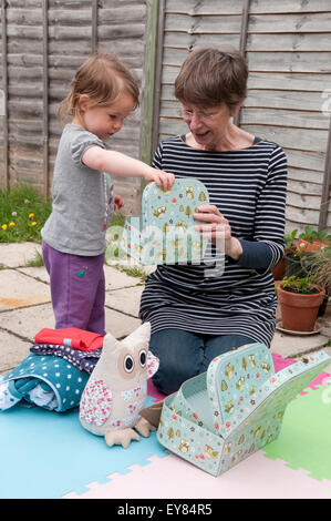 Little girl opening her birthday presents with her grandmother Stock Photo