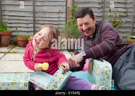 Little girl opening her birthday presents with her grandfather Stock Photo