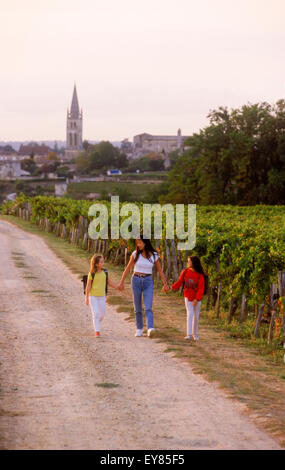 Mother and daughters passing Bordeaux vineyards on way to school in village of   St. Emilion, France Stock Photo