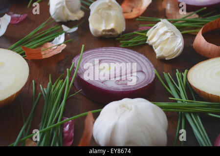 Onions, chives and garlic scattered on wood table for food preparation and cooking concept, with applied retro vintage style fil Stock Photo