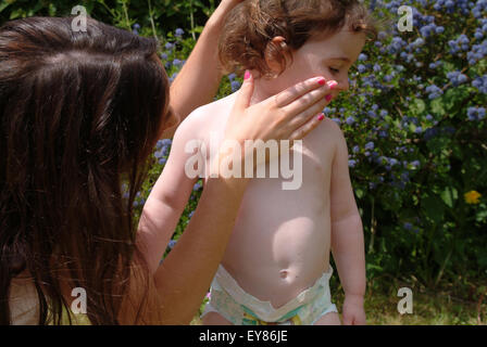 Mother applying suncream on toddlers face Stock Photo