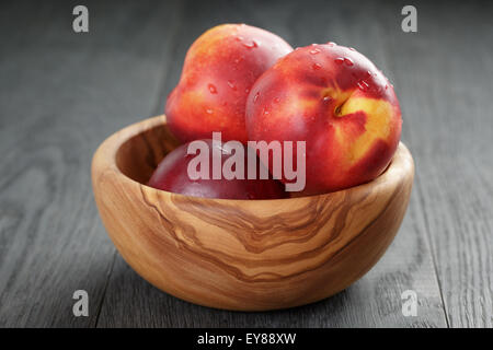 nectarines in olive wood bowl on oak table Stock Photo