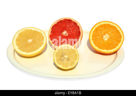Halves of yellow and red grapefruit, orange and lemon set on white plate Stock Photo