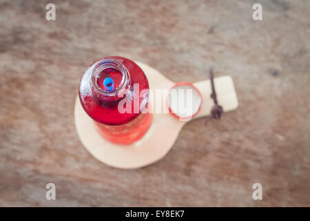 Red syrup in the bottle on wooden plate, stock photo Stock Photo