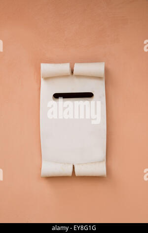 white marble mail box shaped  like an old  paper sheet on a pink painted wall Stock Photo