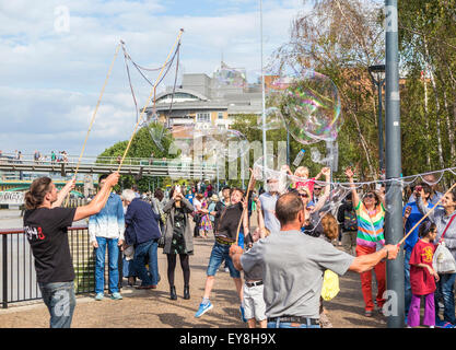 Street entertainers blowing huge bubbles entertaining children and for tips, Bankside, South Bank, London, UK in summer Stock Photo