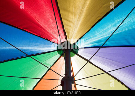 a colorful rainbow colored beach umbrella seen from below Stock Photo