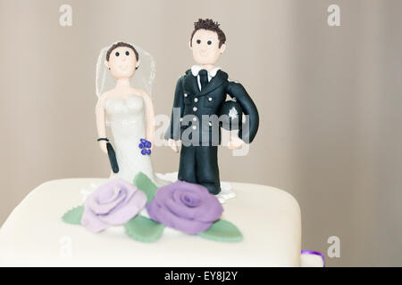 A funny policeman and his bride cake topper, handmade for a couples wedding cake at an English wedding ceremony. the policeman is holding his helmet Stock Photo