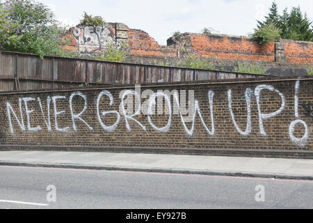 Never Grow Up, white lettering painted on a railway bridge wall Stock Photo