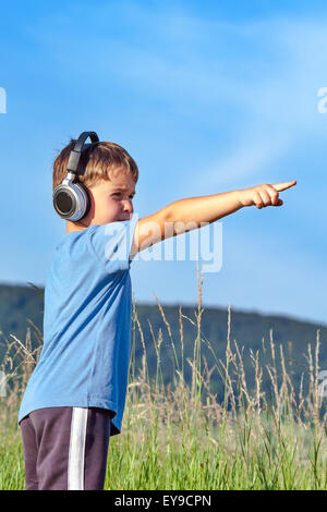 Cute 6 year old boy listening to music on headphones in nature Stock Photo