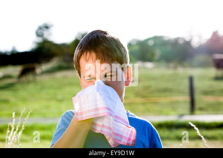 child with an allergy to pollen while you blow your nose with a white handkerchief in nature Stock Photo