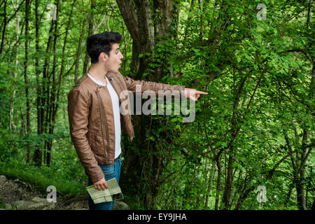 Astonished Looking Young Man Pointing into Distance in Wooded Area, Looking at Something Amazing While on Hike Through Forest Stock Photo