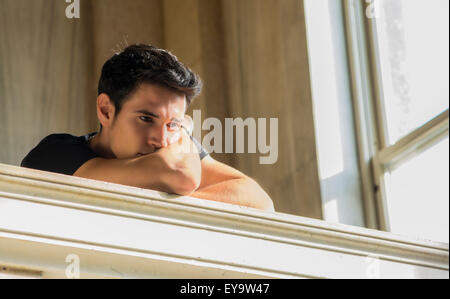 Portrait of Shy Attractive Young Man Leaning on Folded Arms Against Polished Marble Staircase Railing Inside Classical Building Stock Photo