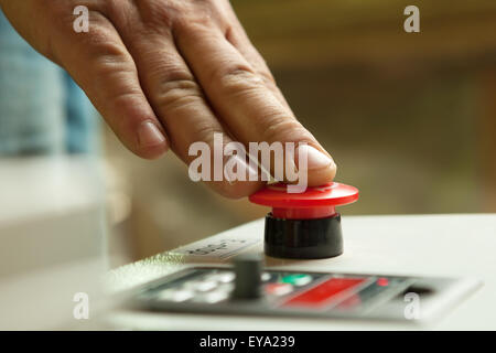 Male hand pushing emergency red stop button. Stock Photo