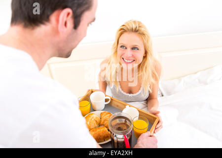 View of a Man bringing young attractive woman breakfast in bed Stock Photo