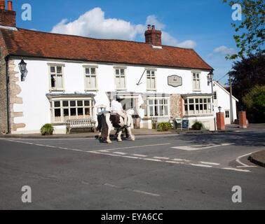 Two people riding horses the village of Ramsbury, Wiltshire, England, UK Stock Photo