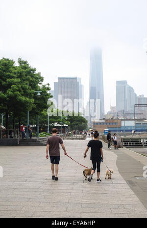 Couple walking their dogs, jogging at Hudson river park. Manhattan, Freedom Tower in background. NYC. USA. Stock Photo