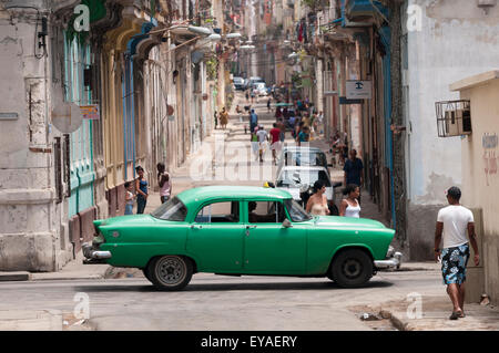 HAVANA, CUBA - JUNE 13, 2011: Vintage green American taxi passes a long, empty street in Central Havana. Stock Photo