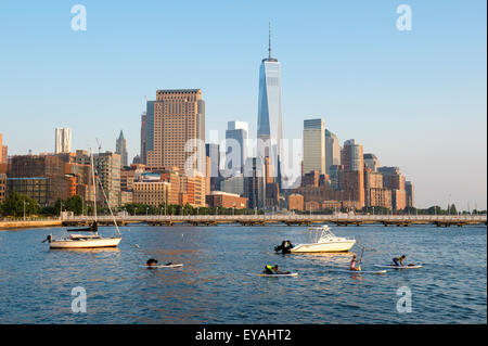 NEW YORK CITY, USA - JULY 12, 2015: People perform yoga exercises on stand up paddle surfboards against the Hudson River skyline Stock Photo