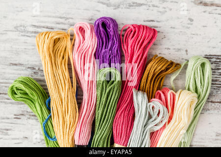 Threads for embroidery from different colors on white wooden background Stock Photo