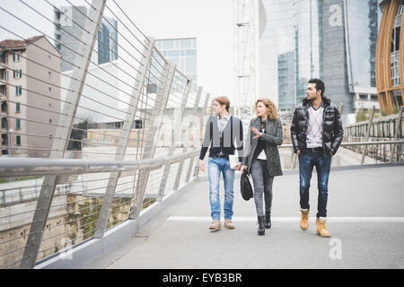 Multiracial contemporary business people walking on a brige in town, talking to each other overlooking - business, finance concept Stock Photo