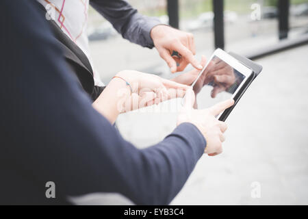 Close up of a group of business people having a meeting outside in the city using tablet  - business, teamwork, multitasking, technology, meeting concepts - Focus on hands Stock Photo
