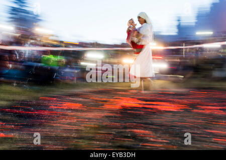 Rozhen, Bulgaria - July 18, 2015: A nestinar woman with a child is walking on fire during a nestinarstvo show. The fire ritual i Stock Photo