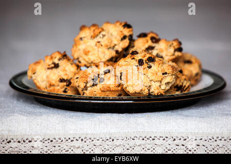 A plate of freshly baked Rock Cakes on a plate placed on a table with a linen table cloth Stock Photo
