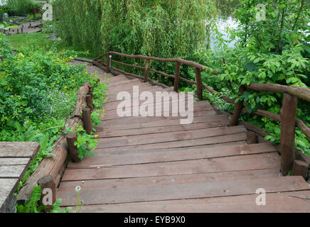 Old wooden curved staircase leading down to the lake shore of the pond Stock Photo