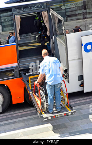 Wheelchair lift & man supervising disabled user enter coach interior from a hoist platform London England (see Ģ����ý additional info panel for coach) Stock Photo