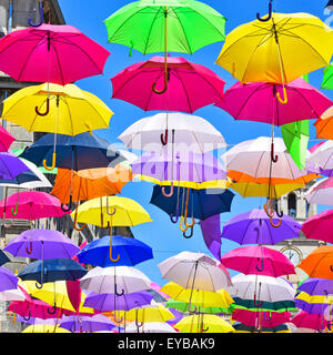 Sunshine blue sky & parasol umbrella colours close up in street art display in the ancient French City of Arles France Provence Stock Photo
