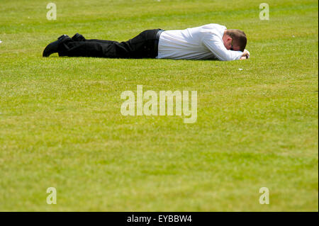 A stressed office worker lies facedown on the grass. Stock Photo