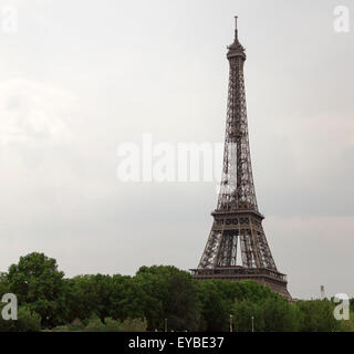 Eiffel Tower in Paris, France with clouds behind it and trees in front of it. Stock Photo