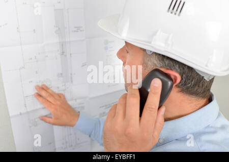 Man on phone looking at plans Stock Photo