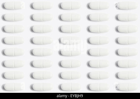 many pills / capsules arranged in row to a medical pattern background Stock Photo