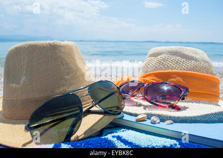 Sun hats and glasses on beach by the water Stock Photo - Alamy