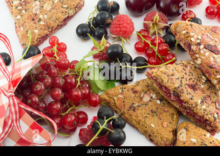 Colorful red berry fruit falling out of decorated box and integral cookies snack on white background Stock Photo