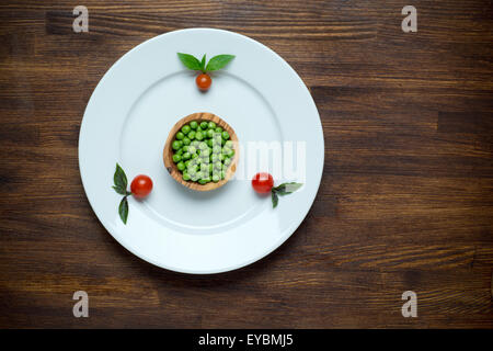 Healthy food theme: green peas on a plate with tomato cherry. Wooden table background Stock Photo