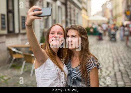 Two young cute teen girls girlfriend take a selfie on smartphone outdoors in the old town. Stock Photo
