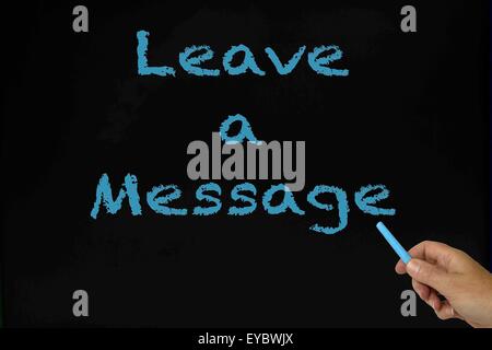 Leave a message written on chalkboard in blue with woman's hand holding the piece of chalk. Stock Photo