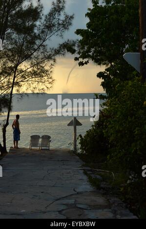 Hope Town, Abaco, Bahamas. 26th July, 2015. A water spout crosses the Abaco Sea between Man-of-War and Hope Town. Oxford resident, Stephen Charters, stands at the end of the lane watching the storm pass Hope Town, which is on the island of Elbow Cay in Abaco, Bahamas. Photo by Sidney Bruere/Alamy Live News Stock Photo