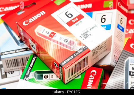 Canon printer ink boxes each housing a color ink cartridge. Scattered in pile with red ink cartridge box on top. Stock Photo