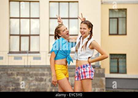 Best friends teenagers met at a summer park. Girls dressed in shorts and a shirt. Teens having fun on summer vacation. Stock Photo