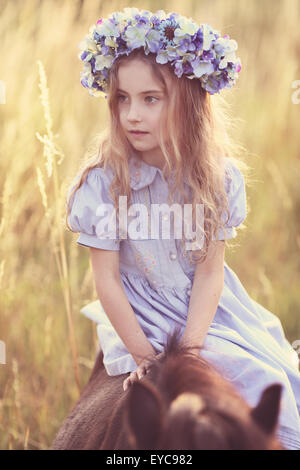 Young girl sitting on a pony in a wreath Stock Photo