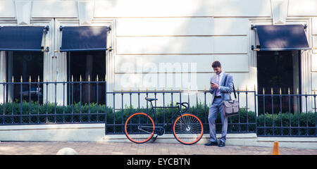 Full length portrait of a happy businessman using smartphone outdoors Stock Photo