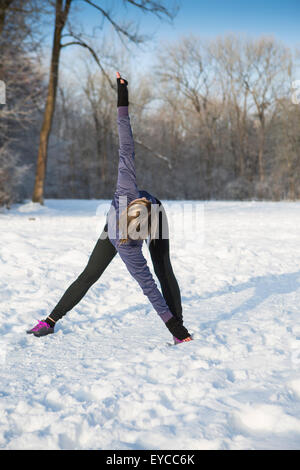 Young woman stretching in snow Stock Photo