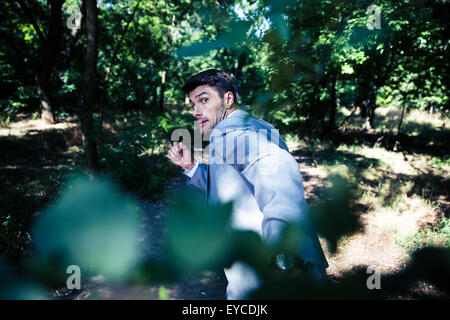 Afraid businessman running away from something outdoors in park Stock Photo