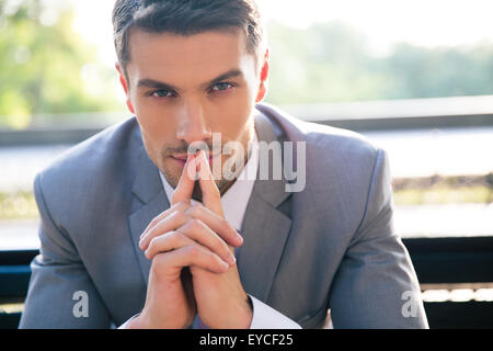 Portrait of a thoughtful businessman sitting on the bench outdoors Stock Photo